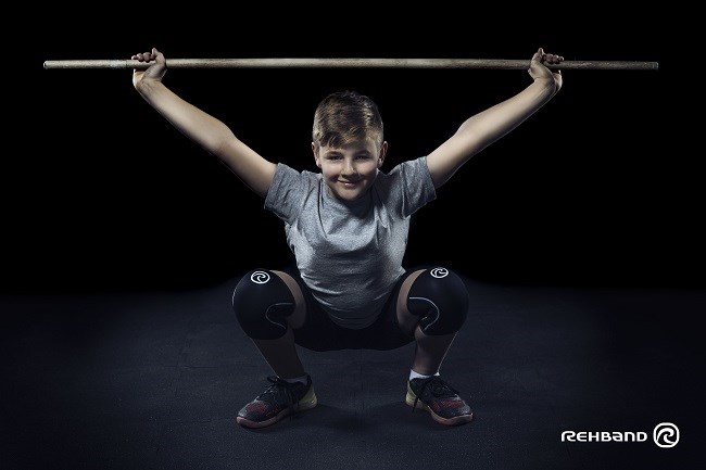 Kille utfr en overhead squat med pinne och Rehbands knskydd.