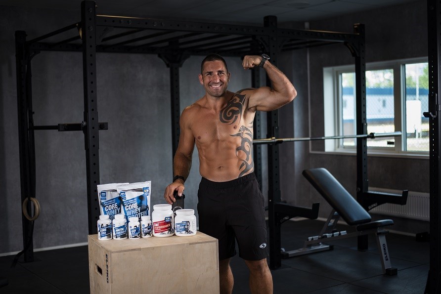 Peter Bláha i gymmiljö med några produkter från Svenskt Kosttillskott. Peter Bláha i gymmiljö med några produkter från Svenskt Kosttillskott.