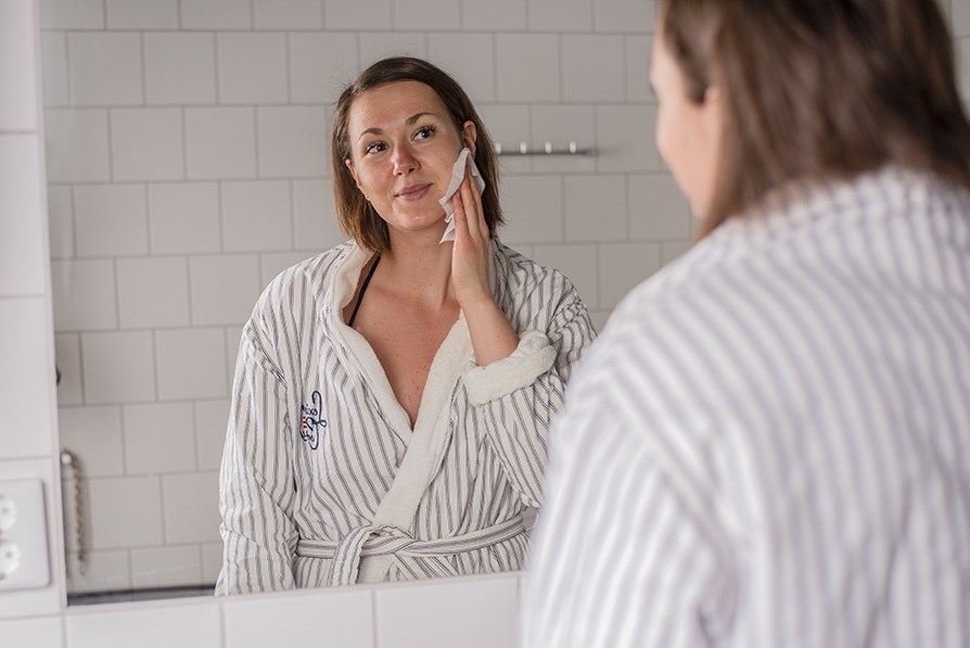 Tjej applicerar brun utan sol med servett i ansiktet.