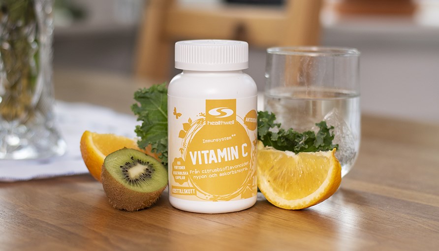 C-vitamin burk uppstlld p ett bord bredvid en bit kiwi och citron. 