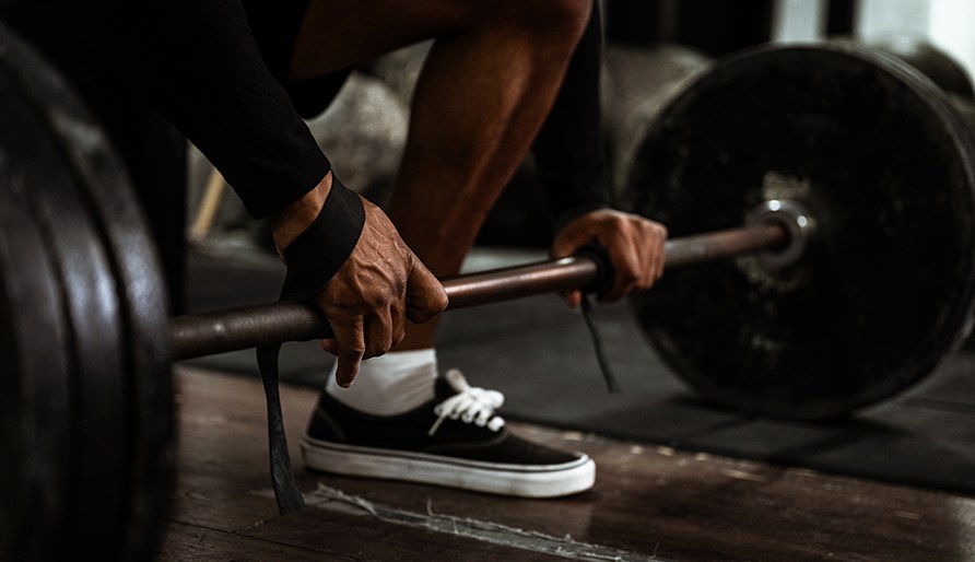 En person som anv�nder dragremmar p� en skivst�ng lastad med vikter under styrketr�ning.