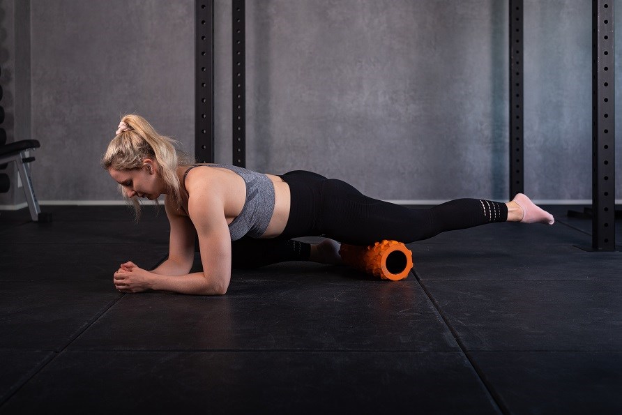 Tr�nande tjej anv�nder foam roller f�r benet.