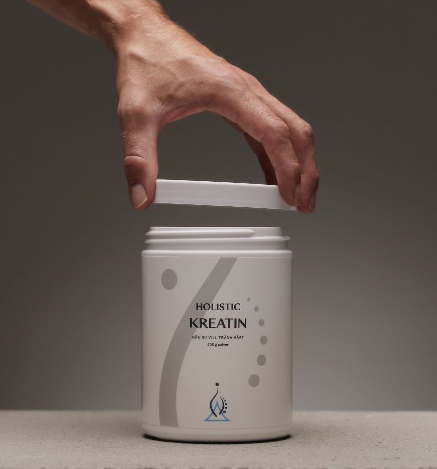 En hand ppnar locket till en burk kreatin frn Holistic. 