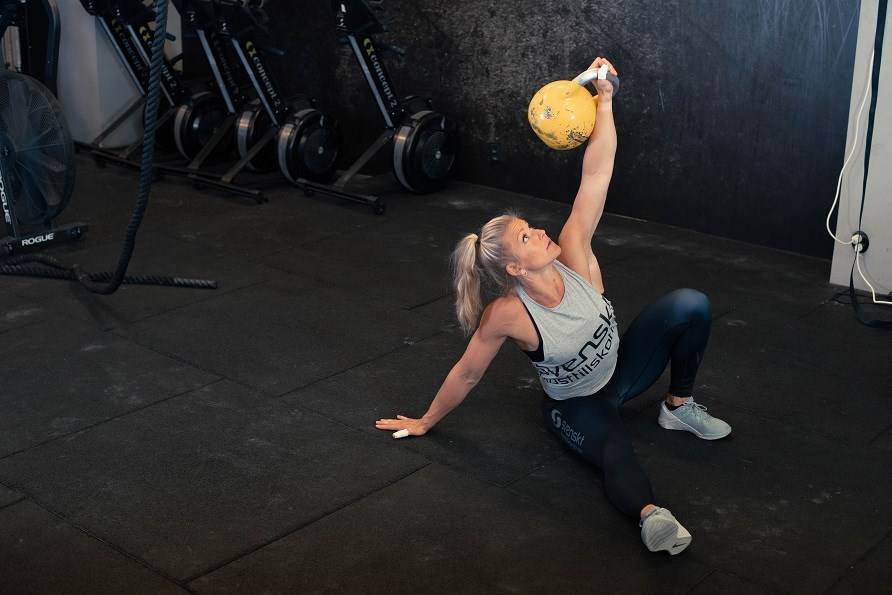 Kvinna p gym utfr vnignen turkish get up med kettlebell.