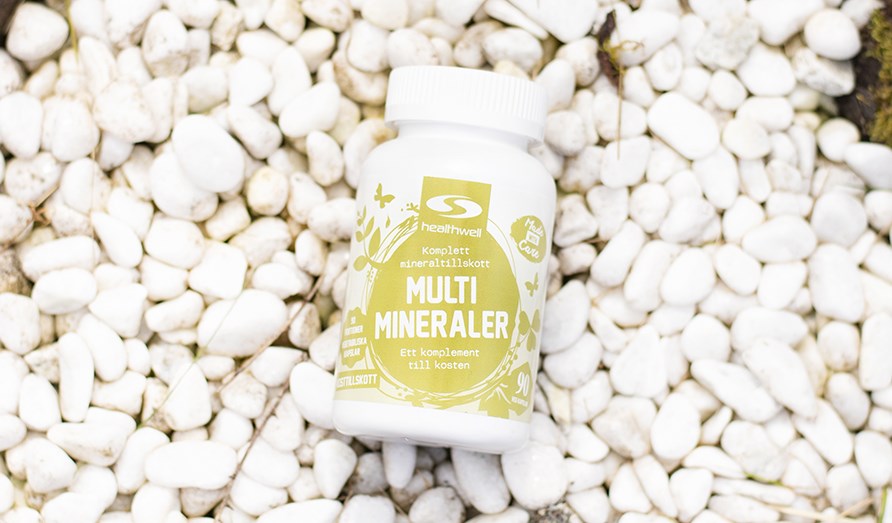 Bild p en burk Healthwell Multimineraler som ligger p vita stenar.