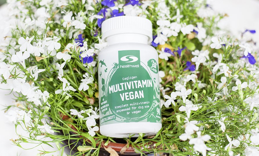 En burk Multivitamin Vegan p en bdd av blommor. 