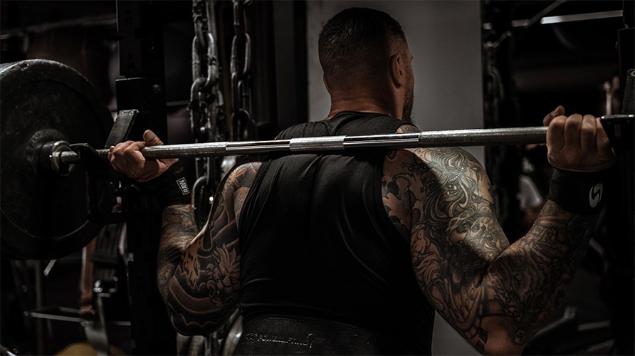 En man med muskuls rygg str vid en skivstng.