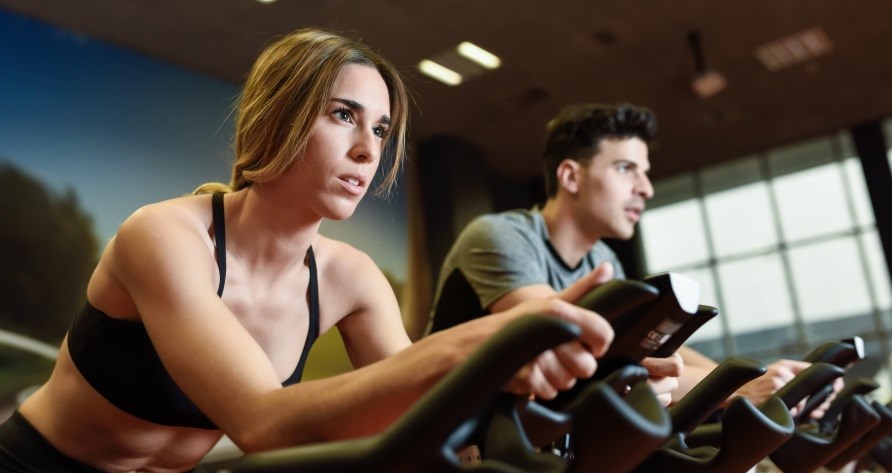 Kvinna och man sitter p varsin spinningcykel.