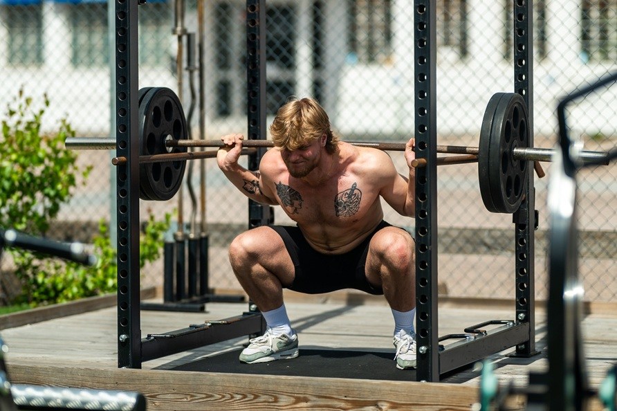 En man utfr trningsvningen knbj utomhus. 