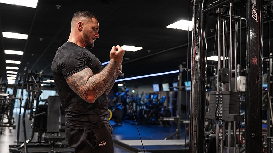 En man utfr bicepscurl i kabelmaskin p gym.