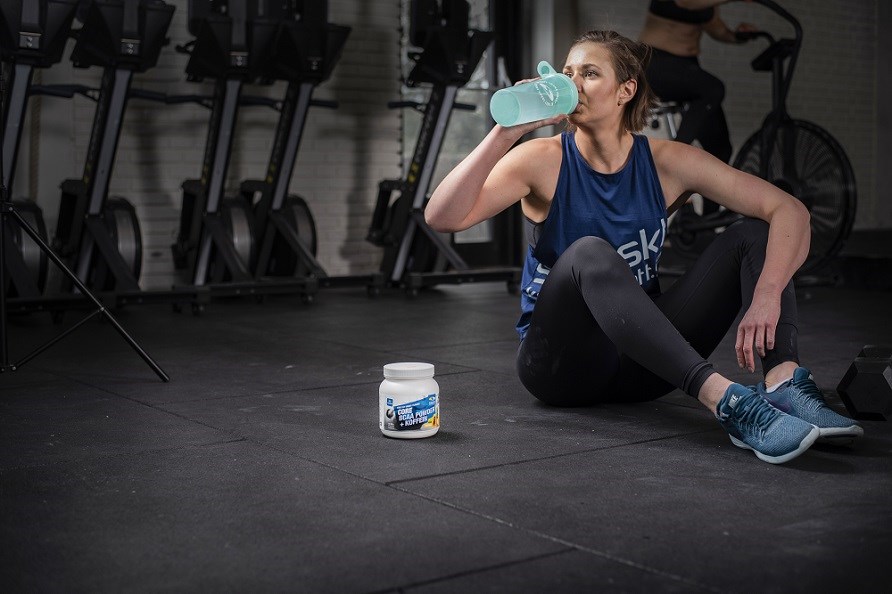 Kvinna som sl�cker t�rsten under tr�ningen med en pre-workout.