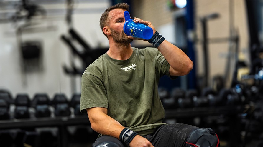 Man som dricker en sportdryck ur en shaker p gymmet